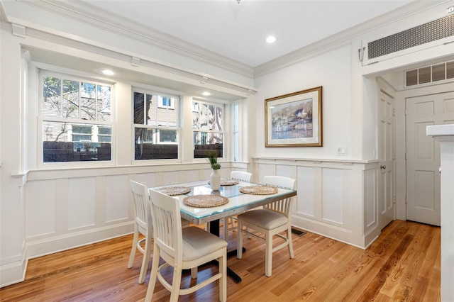 dining area featuring visible vents, light wood-style flooring, recessed lighting, crown molding, and a decorative wall