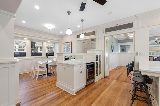 kitchen with a kitchen bar, beverage cooler, crown molding, and a decorative wall