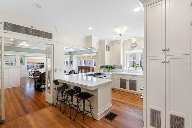 kitchen with light wood-type flooring, a sink, a peninsula, a breakfast bar area, and range