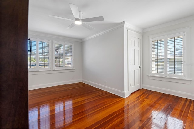 empty room with a ceiling fan, baseboards, wood-type flooring, and ornamental molding