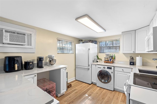 kitchen featuring light wood finished floors, light stone counters, white cabinets, white appliances, and washer / clothes dryer