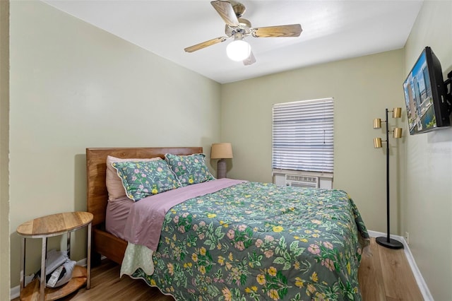 bedroom featuring a ceiling fan, cooling unit, wood finished floors, and baseboards