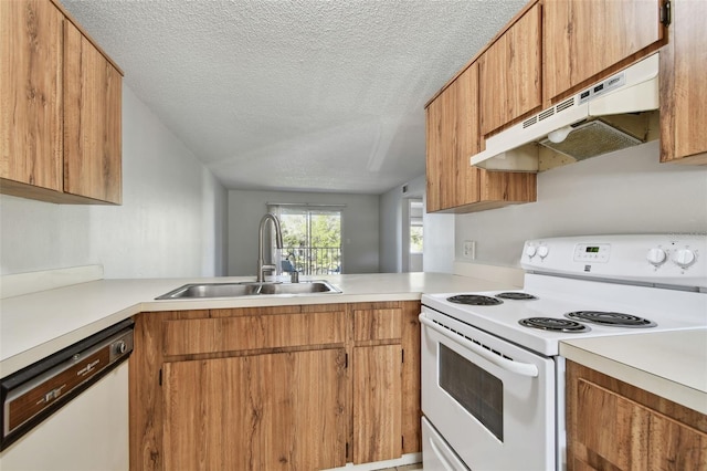 kitchen featuring white appliances, light countertops, a textured ceiling, under cabinet range hood, and a sink