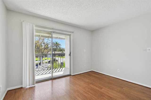 empty room with a textured ceiling, baseboards, and wood finished floors