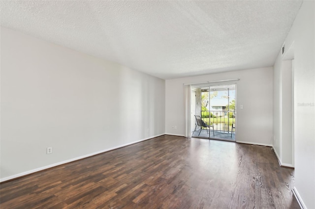 spare room with a textured ceiling, baseboards, and wood finished floors