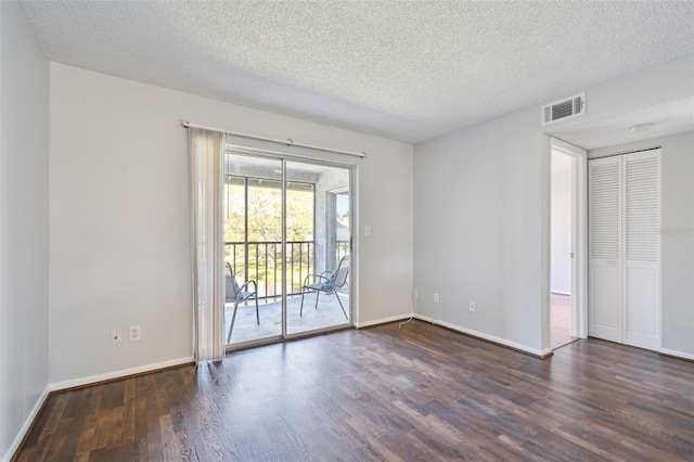 unfurnished room featuring baseboards, a textured ceiling, visible vents, and wood finished floors