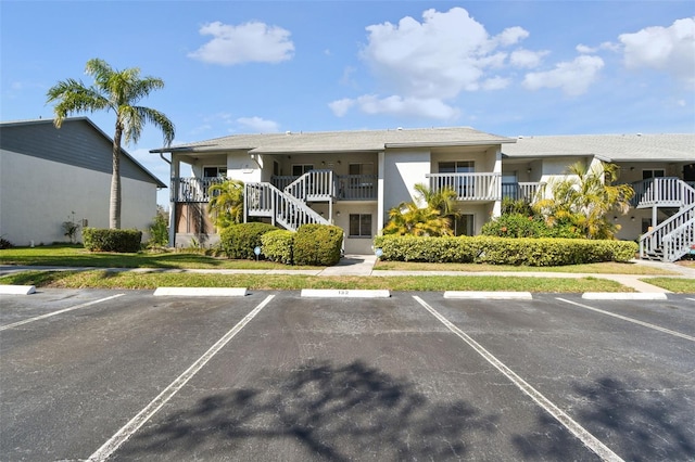 view of property featuring uncovered parking and stairway