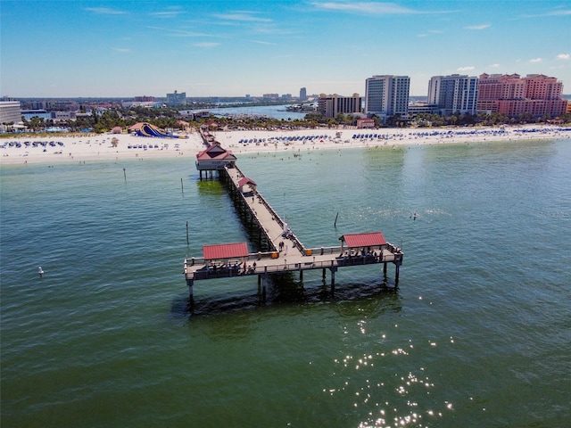 view of dock featuring a water view, a view of city, and a beach view