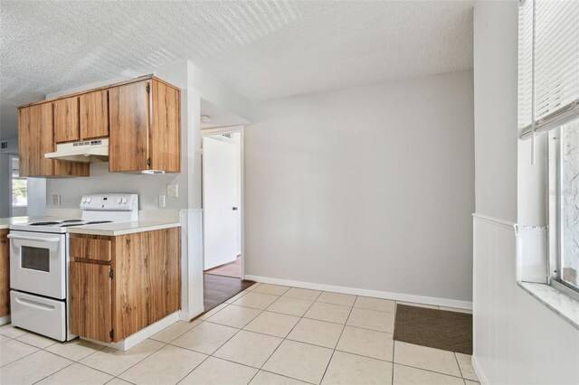 kitchen featuring light countertops, white electric stove, under cabinet range hood, and light tile patterned floors