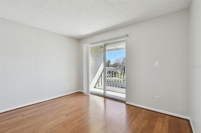 empty room featuring a textured ceiling, baseboards, and wood finished floors