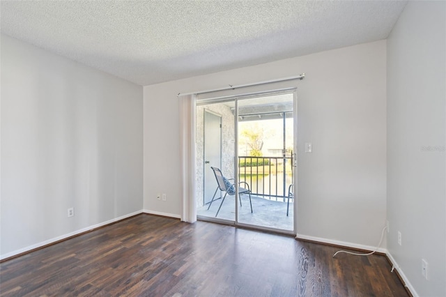 empty room featuring a textured ceiling, baseboards, and wood finished floors