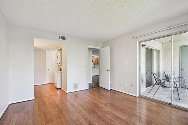 spare room featuring baseboards, a textured ceiling, visible vents, and wood finished floors