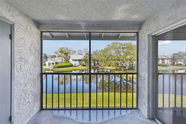 unfurnished sunroom with a residential view and a water view