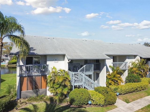 exterior space featuring a water view, stairs, and stucco siding