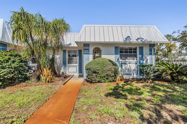 view of front of property featuring a standing seam roof, metal roof, and stucco siding