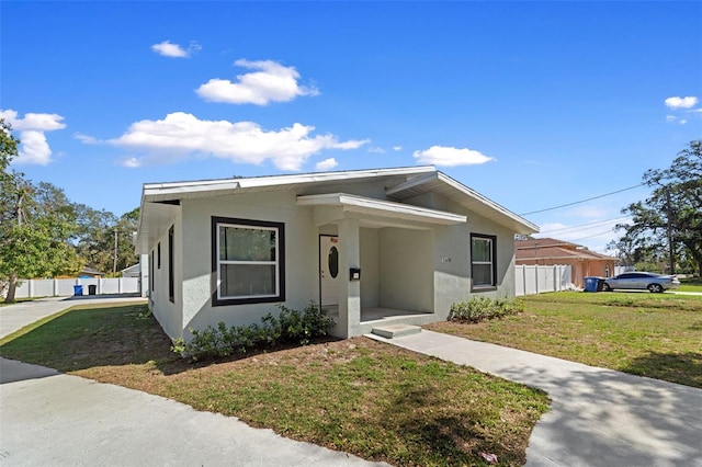 view of front of home featuring a front lawn, fence, and stucco siding