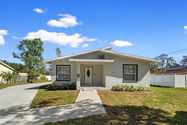 bungalow-style home featuring a front lawn, fence, and stucco siding