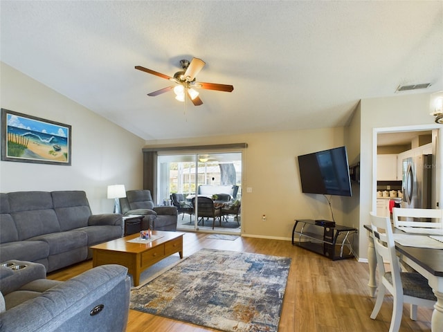 living area with lofted ceiling, visible vents, light wood-style floors, ceiling fan, and baseboards