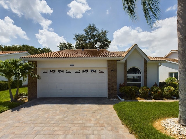 view of front of home with decorative driveway, brick siding, stucco siding, a garage, and a tiled roof