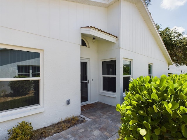 entrance to property featuring stucco siding, a tile roof, and a patio