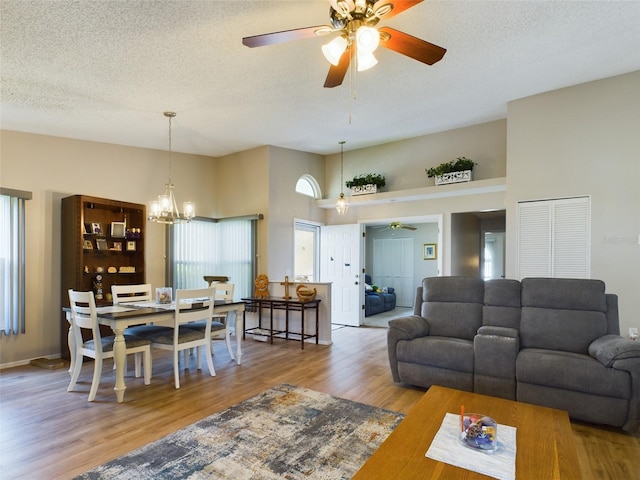 living area featuring a textured ceiling, wood finished floors, and ceiling fan with notable chandelier