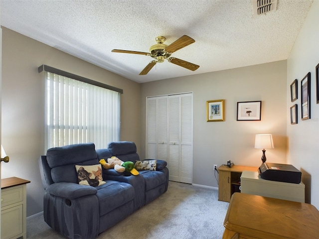 living room with a textured ceiling, visible vents, a ceiling fan, and light colored carpet