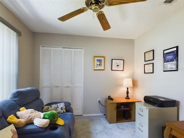 office area featuring baseboards, a ceiling fan, a textured ceiling, and light colored carpet