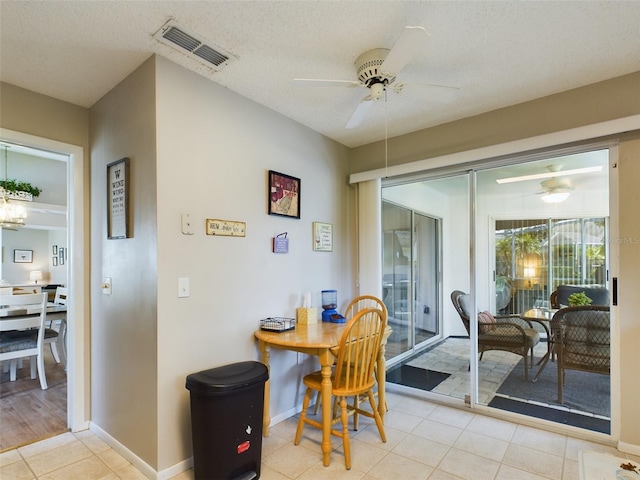 dining space with light tile patterned floors, a textured ceiling, visible vents, baseboards, and a ceiling fan