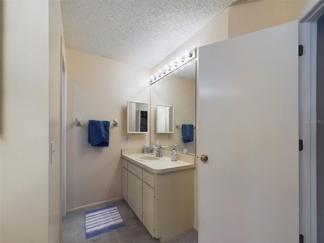 bathroom with baseboards, a textured ceiling, and vanity