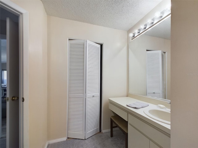 bathroom with baseboards, a textured ceiling, and vanity