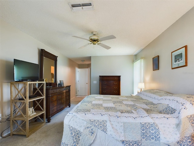 bedroom with ceiling fan, visible vents, a textured ceiling, and light colored carpet