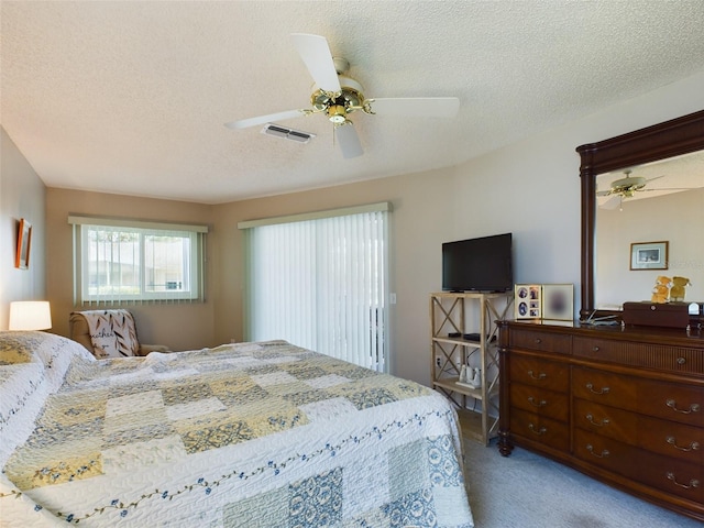 carpeted bedroom featuring a ceiling fan, visible vents, and a textured ceiling