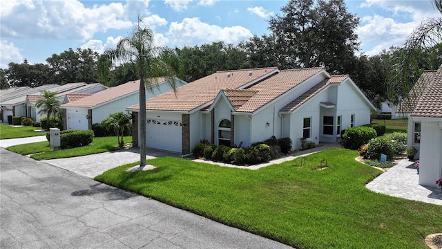 view of front of house featuring a garage, a tiled roof, decorative driveway, stucco siding, and a front yard