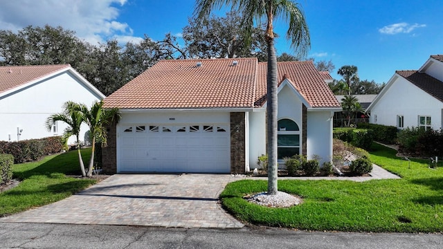 mediterranean / spanish-style home with a garage, a tile roof, decorative driveway, a front lawn, and stucco siding