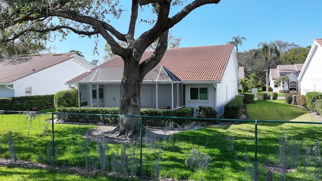 exterior space with glass enclosure, a lawn, fence, and a tiled roof