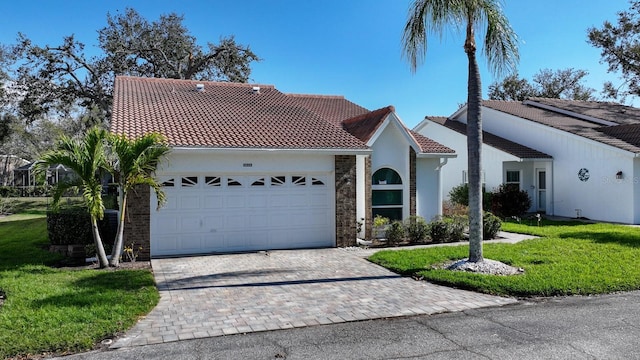 mediterranean / spanish home featuring decorative driveway, stucco siding, a front yard, a garage, and a tiled roof