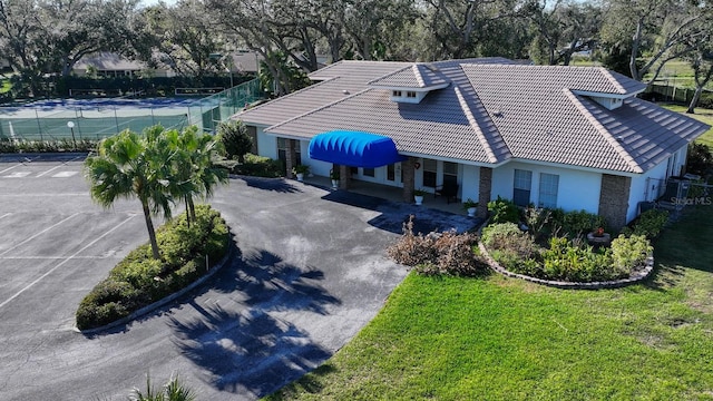 view of front of home with driveway, a tile roof, fence, a front lawn, and stucco siding