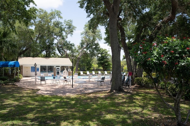 view of yard featuring a storage structure, a community pool, a patio, and an outbuilding