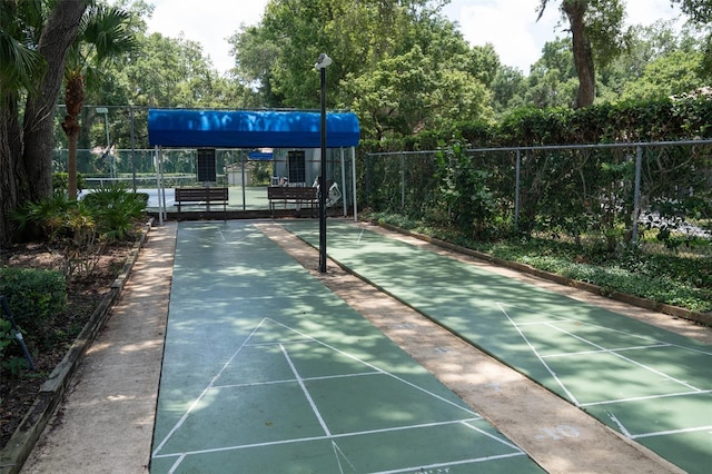 view of property's community with shuffleboard and fence