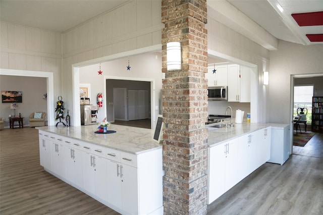 kitchen with light wood-style floors, stainless steel microwave, white cabinets, and a sink