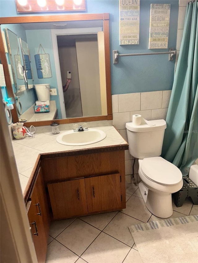 full bath with toilet, vanity, tile walls, wainscoting, and tile patterned floors