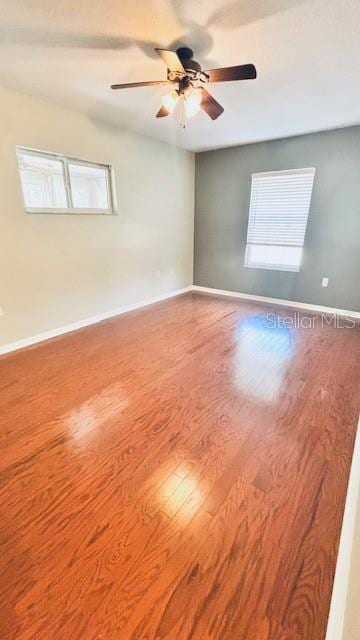 spare room with wood finished floors, a ceiling fan, and baseboards