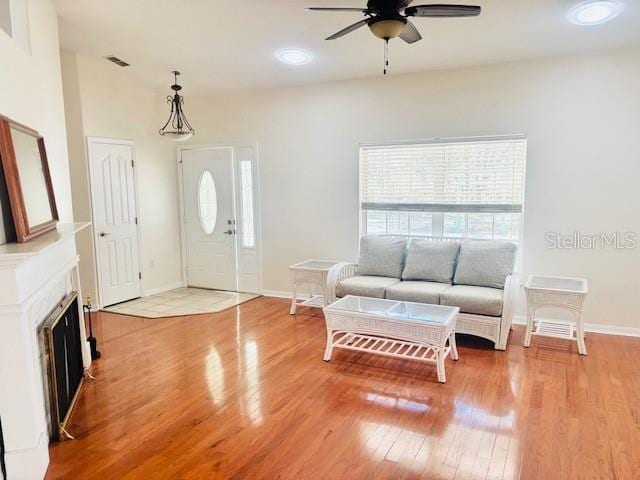 living room with a fireplace, plenty of natural light, light wood finished floors, and ceiling fan