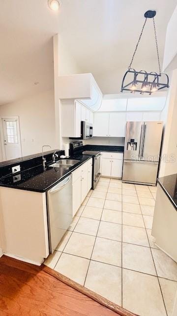 kitchen featuring stainless steel appliances, light tile patterned flooring, a sink, and white cabinets