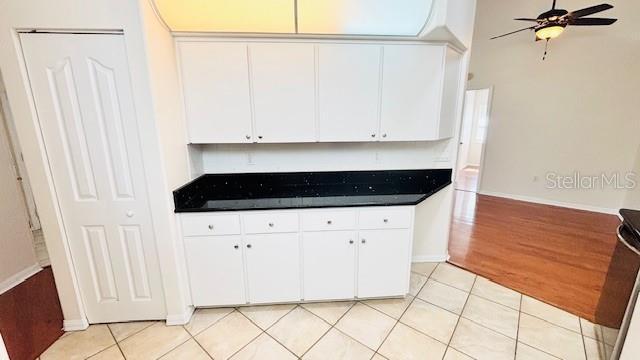 kitchen featuring dark countertops, light tile patterned flooring, and white cabinetry