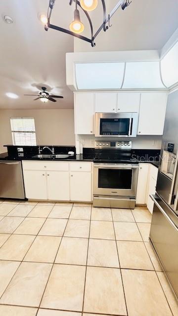 kitchen featuring dark countertops, white cabinetry, appliances with stainless steel finishes, and a sink