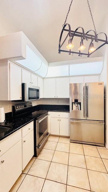 kitchen with dark countertops, light tile patterned floors, white cabinetry, and stainless steel appliances