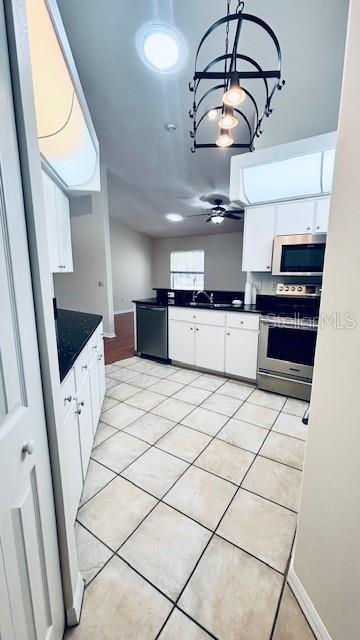 kitchen featuring stainless steel appliances, dark countertops, white cabinets, and light tile patterned floors