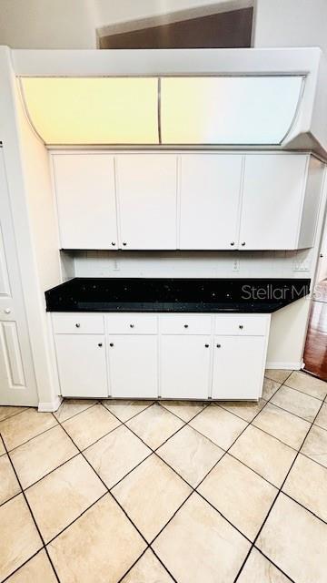 kitchen with dark countertops, white cabinets, and light tile patterned floors