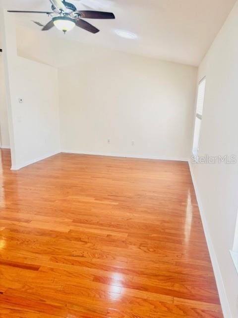 spare room with lofted ceiling, light wood finished floors, ceiling fan, and baseboards